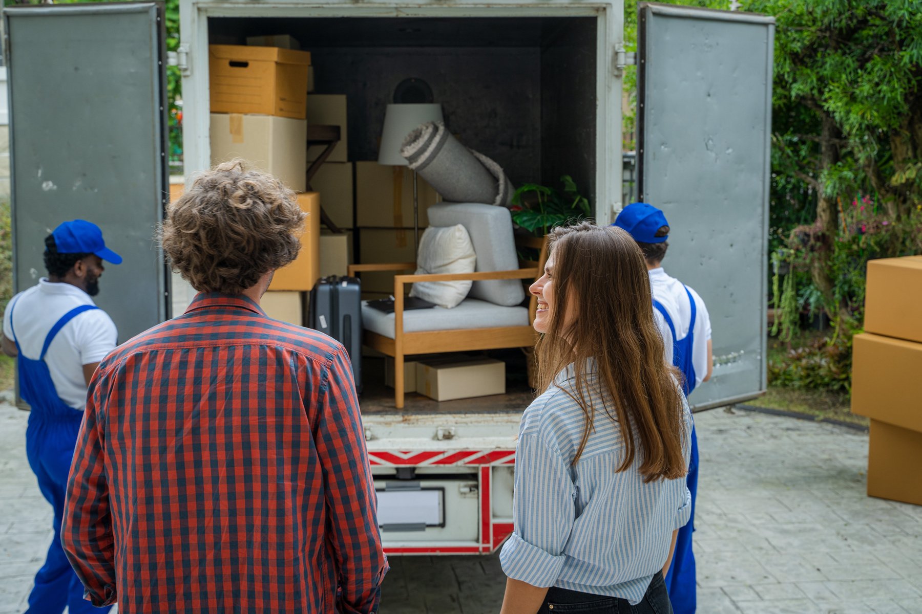 Happy couple with moving boxes at new house,Moving company emplo